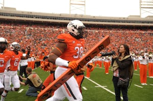Oklahoma State defensive end Emmanuel Ogbah (38) carries the team's Big Stick onto the field at the start of an NCAA college football game between Kansas and Oklahoma St in Stillwater, Okla., Saturday, Oct. 24, 2015.(AP Photo/Brody Schmidt)